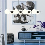 Lampa wisząca Rory 8-punktowa w kolorze czarnym z opalowymi kloszami, zawieszona poziomo nad niebieskim stolikiem. Klosze mają okrągły kształt, a całość uzupełniają nowoczesne elementy dekoracyjne w tle.