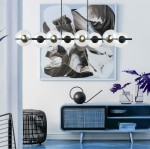 Lampa wisząca Rory, 8-punktowa, w kolorze czarnym i przezroczystym, z okrągłymi kloszami, zawieszona nad niebieskim stolikiem, w nowoczesnym wnętrzu. Tło z abstrakcyjnym obrazem i dekoracjami w minimalistycznym stylu.