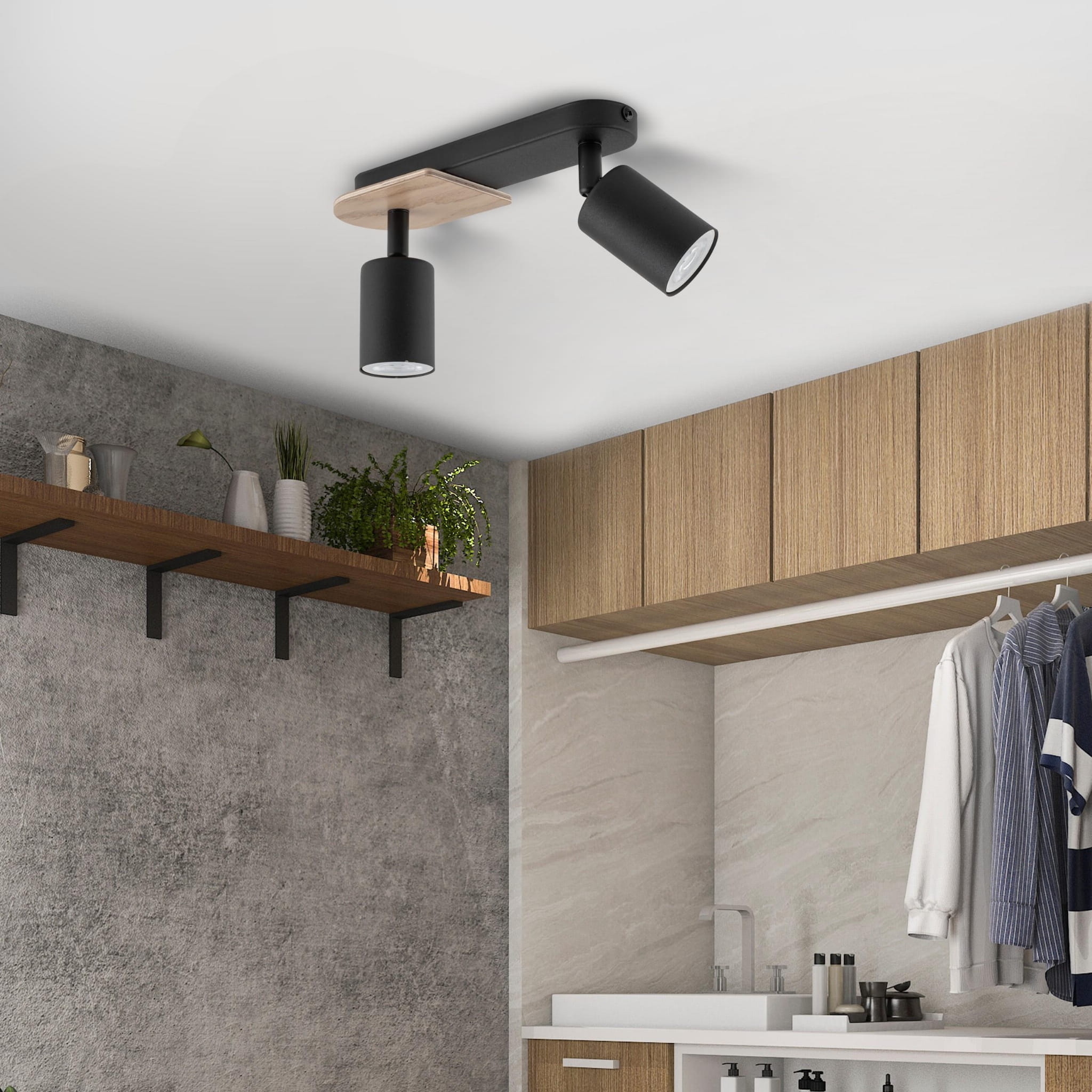 Czarna lampa sufitowa (spot) 2-punktowa Cover Wood z drewnianym elementem, zamontowana na suficie. Reflektory skierowane w dół, w nowoczesnym wnętrzu z drewnianymi meblami i szarymi ścianami. Widoczna półka z roślinami w tle.