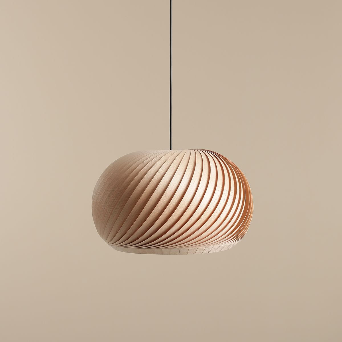 Lampa wisząca Nature Dark D45 ma zaokrąglony klosz z lameli w jasnym drewnie, o spiralnym wzorze. Zawieszona na cienkim czarnym przewodzie, idealna do nowoczesnych wnętrz. Tło w jednolitym jasnym kolorze podkreśla elegancję lampy.