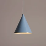 Lampa wisząca Form Dusty Blue, 1-punktowa, w kształcie stożka, w kolorze błękitu morskim. Posiada metalowy klosz z połyskiem, zawieszony na czarnym przewodzie. Tło w odcieniu jasnego beżu.