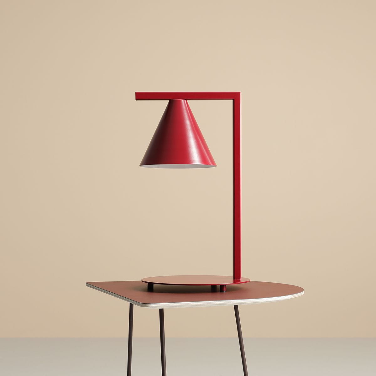 Lampa stołowa Form Red Wine 1-punktowa, z czerwonym, stożkowatym kloszem i prostą, metalową podstawą. Ujęcie frontalne, lampa umieszczona na okrągłej, czerwonej podstawie, w neutralnym tle.