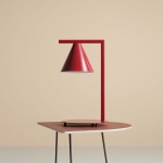 Lampa stołowa Form Red Wine 1-punktowa, z czerwonym, stożkowatym kloszem i prostą, metalową podstawą. Ujęcie frontalne, lampa umieszczona na okrągłej, czerwonej podstawie, w neutralnym tle.