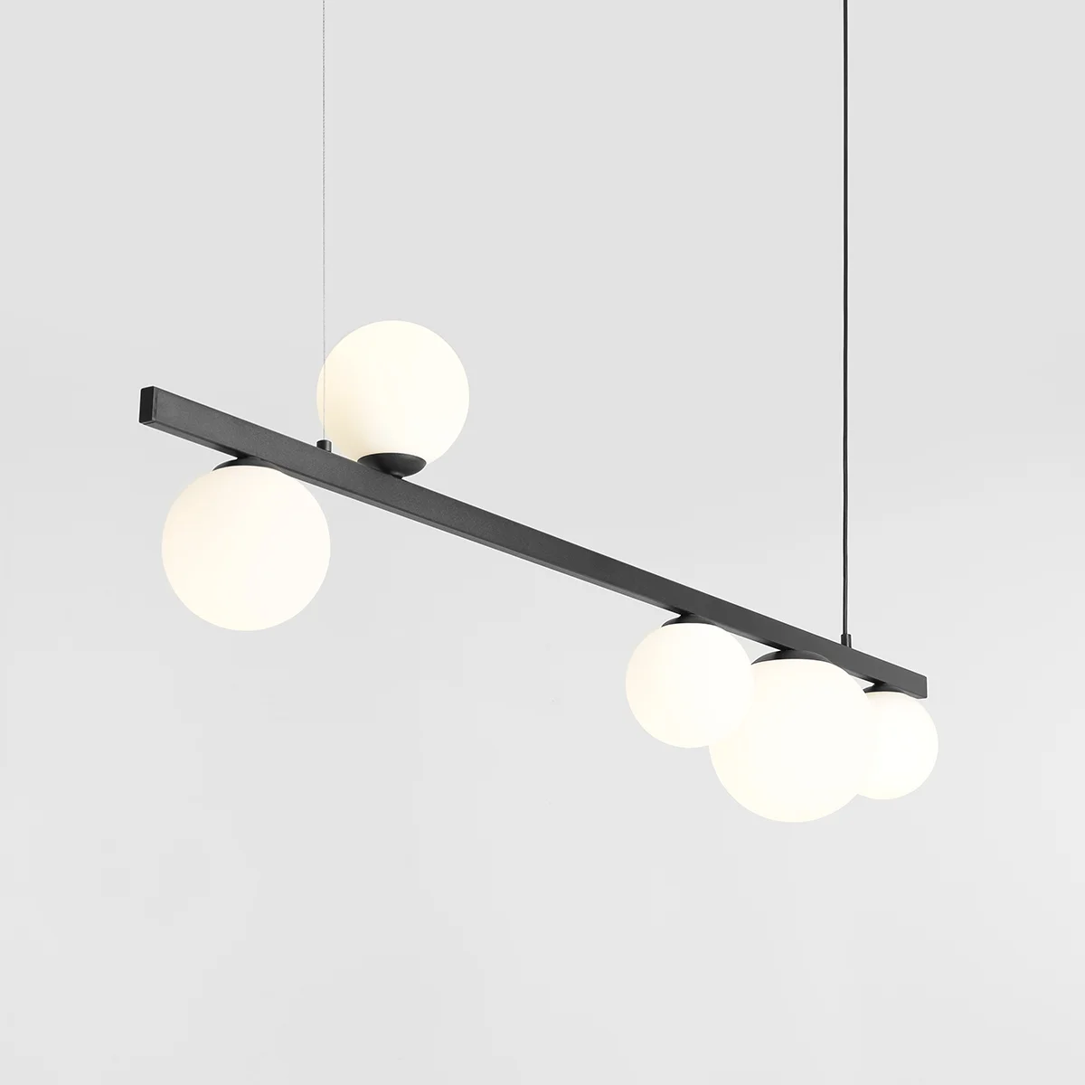 Lampa wisząca Garda 5-punktowa w kolorze czarnym, z prostokątnym stelażem i pięcioma okrągłymi, białymi kloszami. Ujęcie z góry, zawieszona na cienkich linkach, na jasnym tle. Idealna do nowoczesnych wnętrz.
