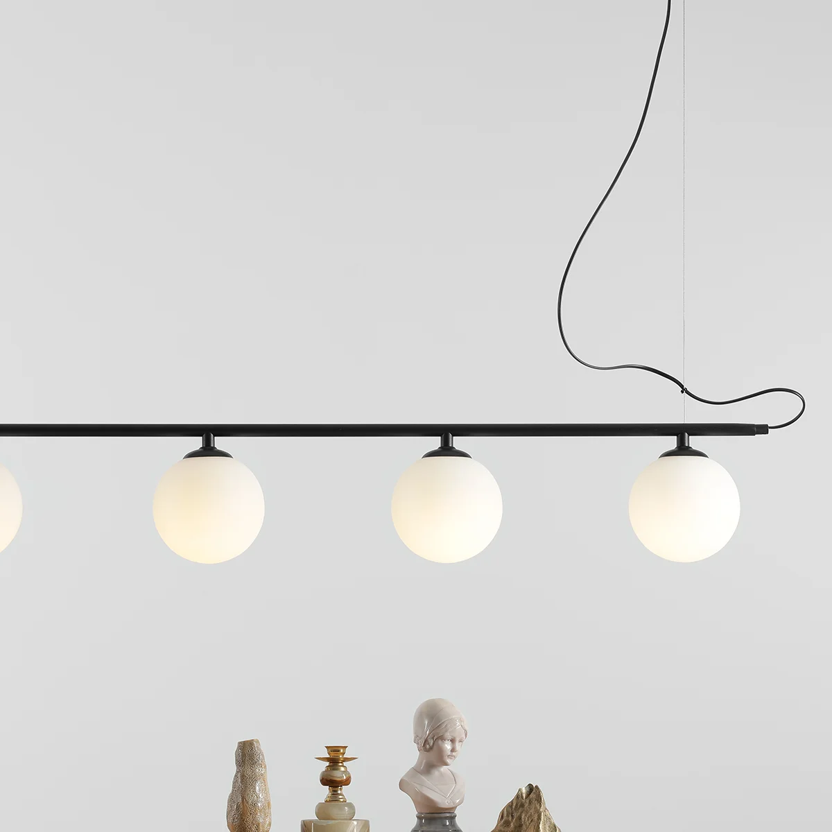 Lampa wisząca Beryl Glass 5-punktowa w czarnym kolorze, z pięcioma okrągłymi kloszami w białym, matowym szkle. Ujęcie z góry, wisząca na czarnym przewodzie, w otoczeniu dekoracji. Idealna do nowoczesnych wnętrz.