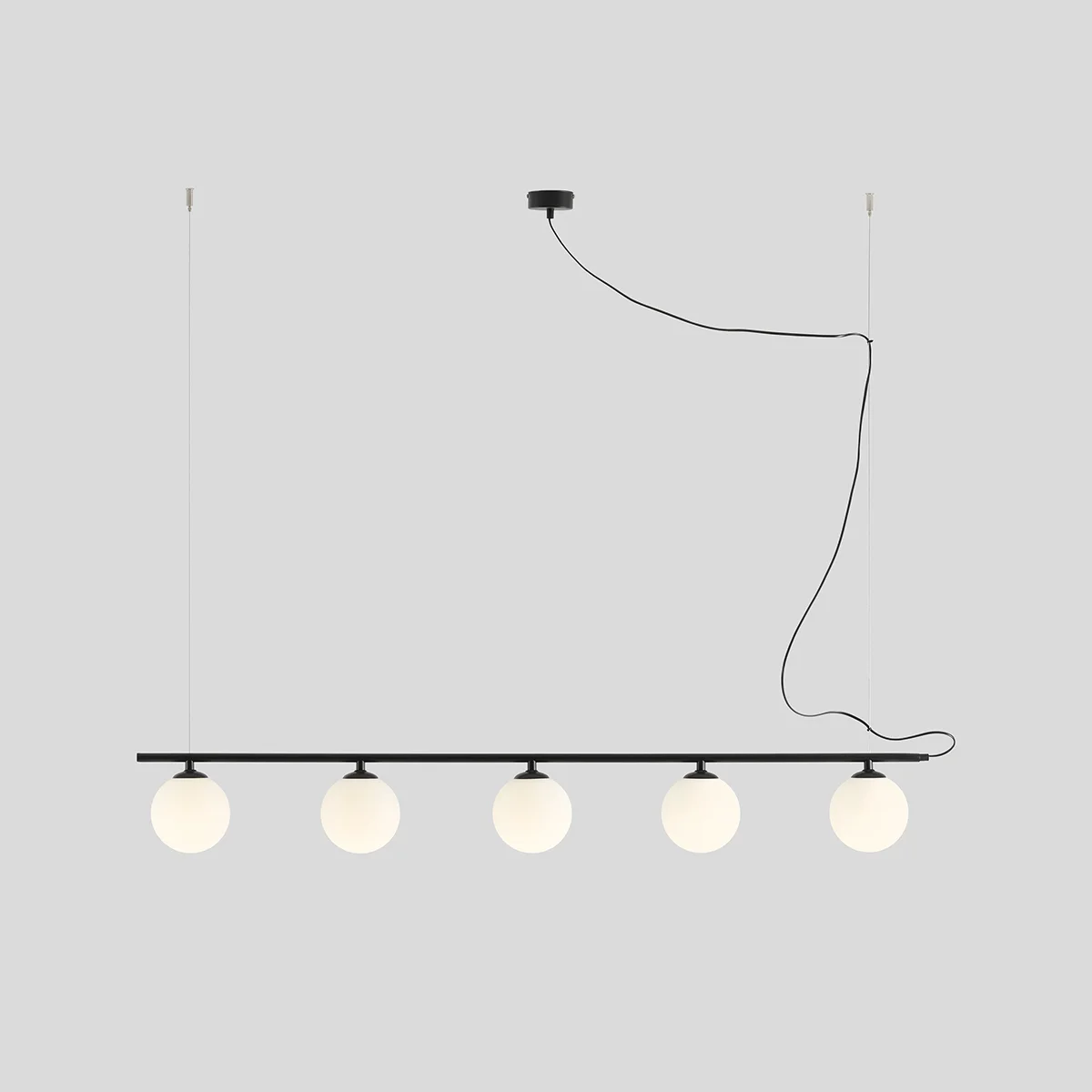 Lampa wisząca Beryl Glass 5-punktowa w kolorze czarnym. Posiada prostą, poziomą konstrukcję z pięcioma okrągłymi kloszami w odcieniu matowej bieli. Zawieszona na cienkich linkach, z widocznym kablem i stropowym mocowaniem.