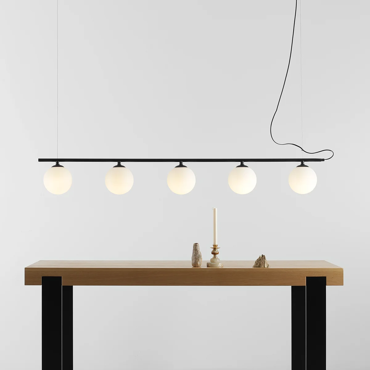 Lampa wisząca Beryl Glass 5-punktowa w kolorze czarnym. Składa się z pięciu białych, okrągłych kloszy zawieszonych na cienkiej, poziomej rurze.