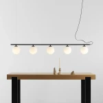 Lampa wisząca Beryl Glass 5-punktowa w kolorze czarnym. Składa się z pięciu białych, okrągłych kloszy zawieszonych na cienkiej, poziomej rurze.