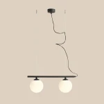 Lampa wisząca Beryl Glass 2-punktowa w kolorze czarnym, z dwiema białymi kulami ze szkła zamocowanymi na poziomej belce. Kabel zasilający w czarnym kolorze, zawieszona na dwóch cienkich linkach. Prosta forma, idealna do nowoczesnych wnętrz.
