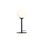 Pinne lampa stołowa 1-punktowa w kolorze czarnym, z okrągłym kloszem z mlecznego szkła. Produkt stoi na okrągłej podstawie z czarnego metalu, z widocznym przewodem zasilającym. Ujęcie z boku.