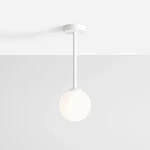 Biała lampa wisząca Pinne Short z okrągłym kloszem, zawieszona na cienkim białym pręcie. Klosz ma matową, półprzezroczystą powierzchnię, a całość umieszczona jest na jasnym tle.