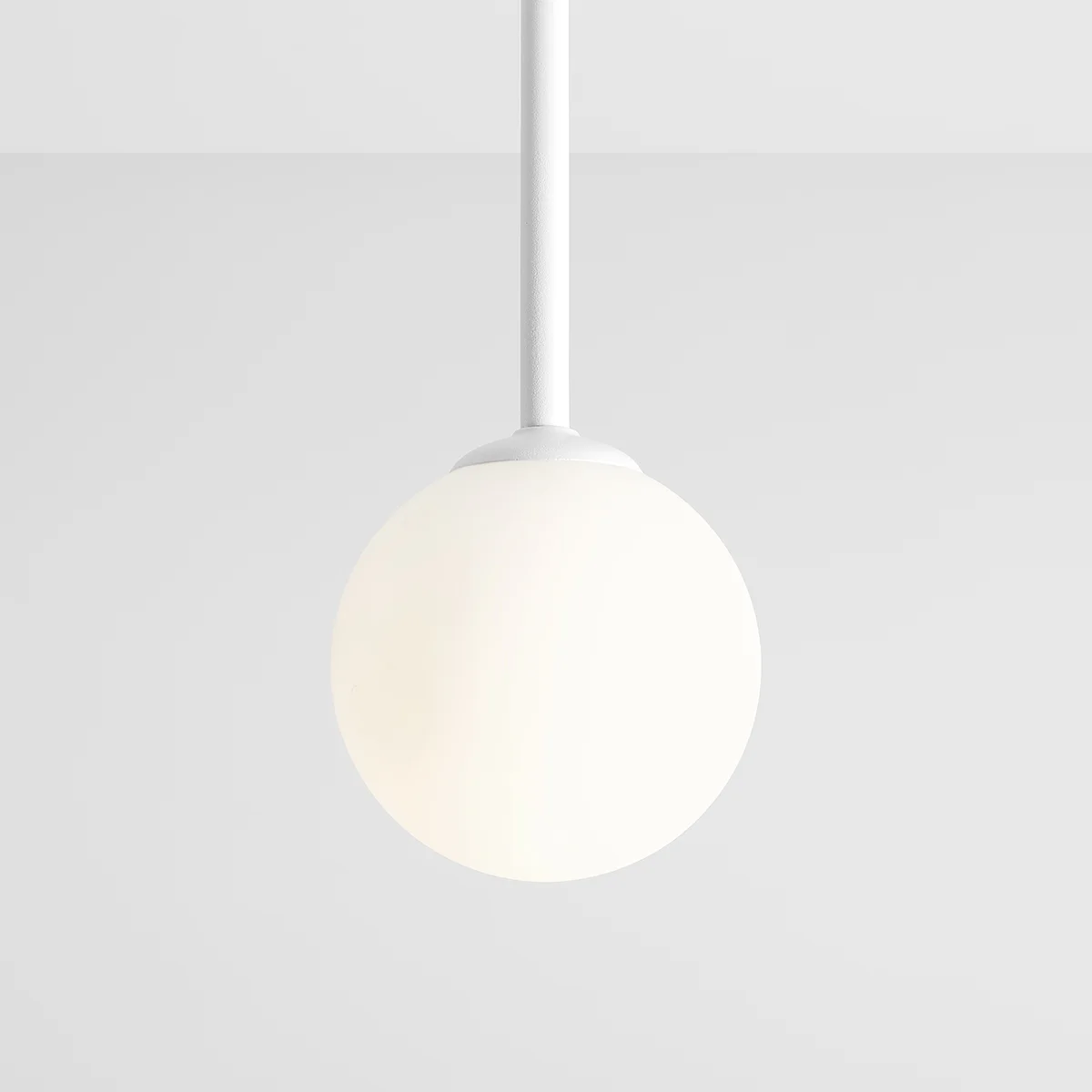 Lampa wisząca Pinne Short 1-punktowa w białym kolorze. Okrągła kula ze szkła matowego zawieszona na cienkim białym przewodzie. Prosty, nowoczesny design, idealna do wnętrz.