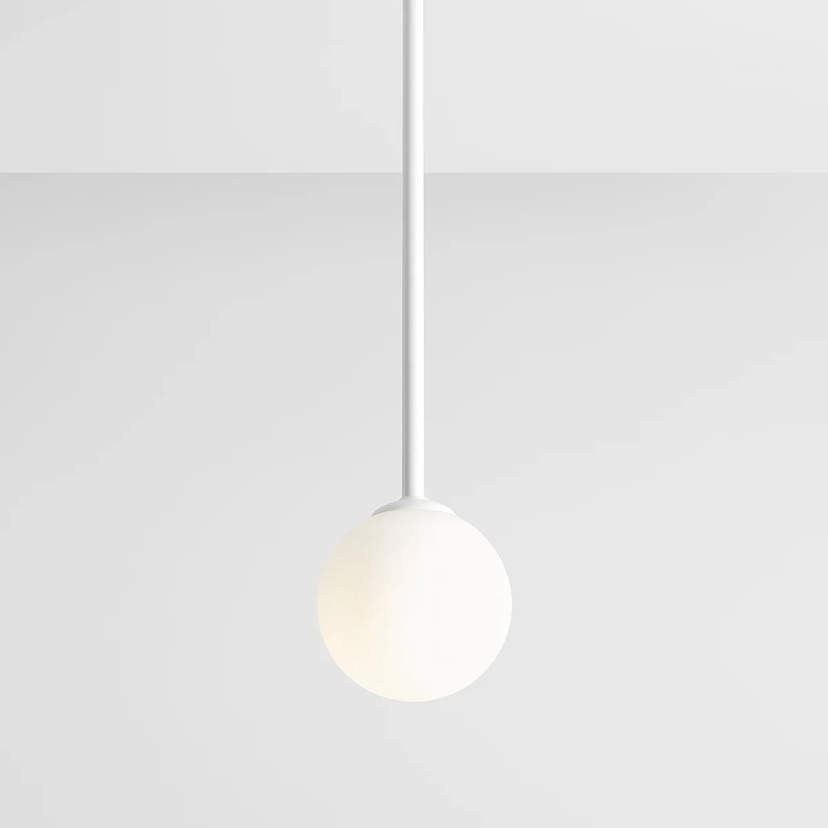 Biała lampa wisząca Pinne Long z pojedynczym punktem świetlnym. Okrągła, matowa kula na cienkim, białym przewodzie. Produkt zawieszony w centralnej pozycji na jednolitym tle.