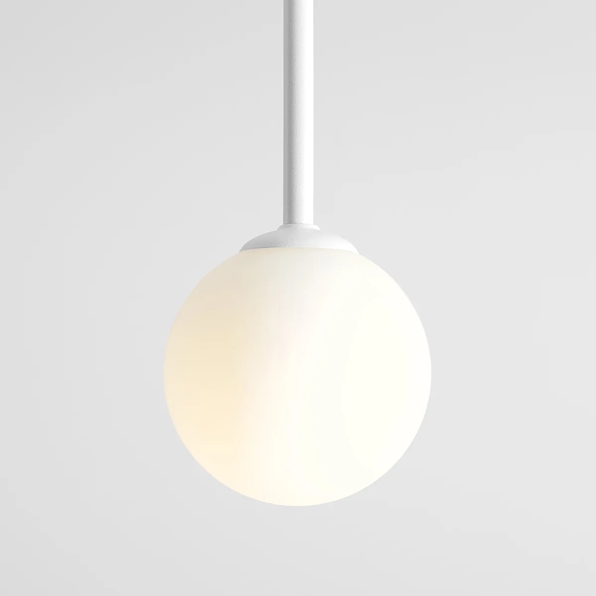 Lampa wisząca Pinne Long 1-punktowa w kolorze białym, z okrągłym kloszem z matowego szkła. Produkt zawieszony na cienkim, białym przewodzie, z minimalistycznym designem, odpowiedni do nowoczesnych wnętrz.