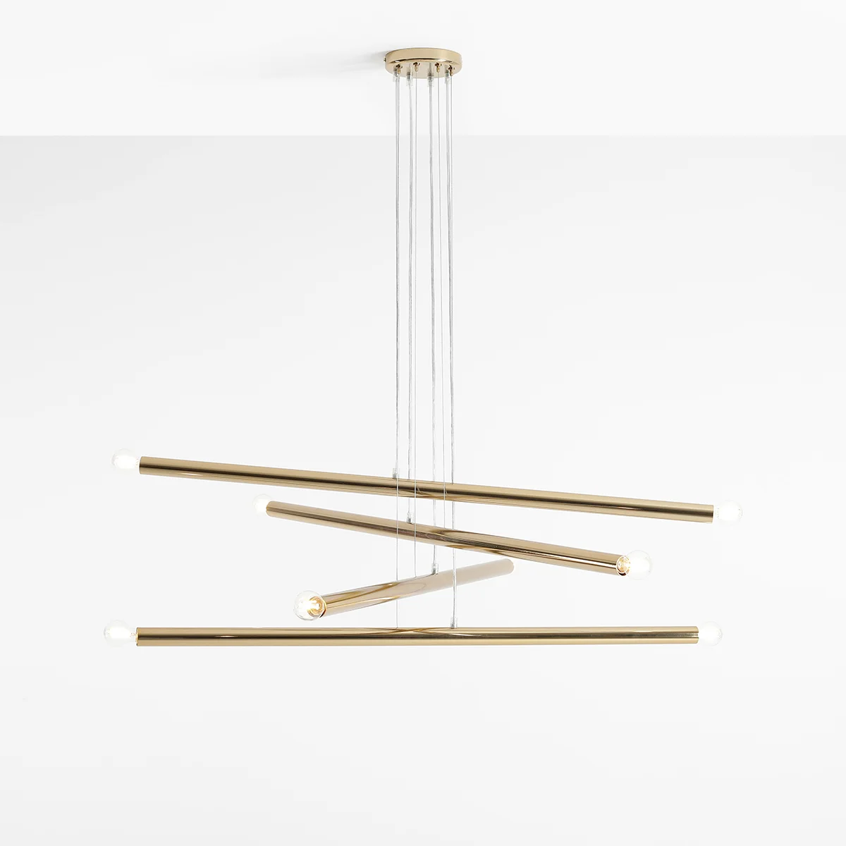 Lampa wisząca Tubo 8-punktowa w kolorze złotym, składająca się z asymetrycznych, długich rur z pięcioma źródłami światła na końcach. Ujęcie z góry, zawieszona na cienkich linkach. Proste tło podkreśla nowoczesny design lampy.