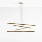 Lampa wisząca Tubo 8-punktowa w kolorze złotym, składająca się z asymetrycznych, długich rur z pięcioma źródłami światła na końcach. Ujęcie z góry, zawieszona na cienkich linkach. Proste tło podkreśla nowoczesny design lampy.