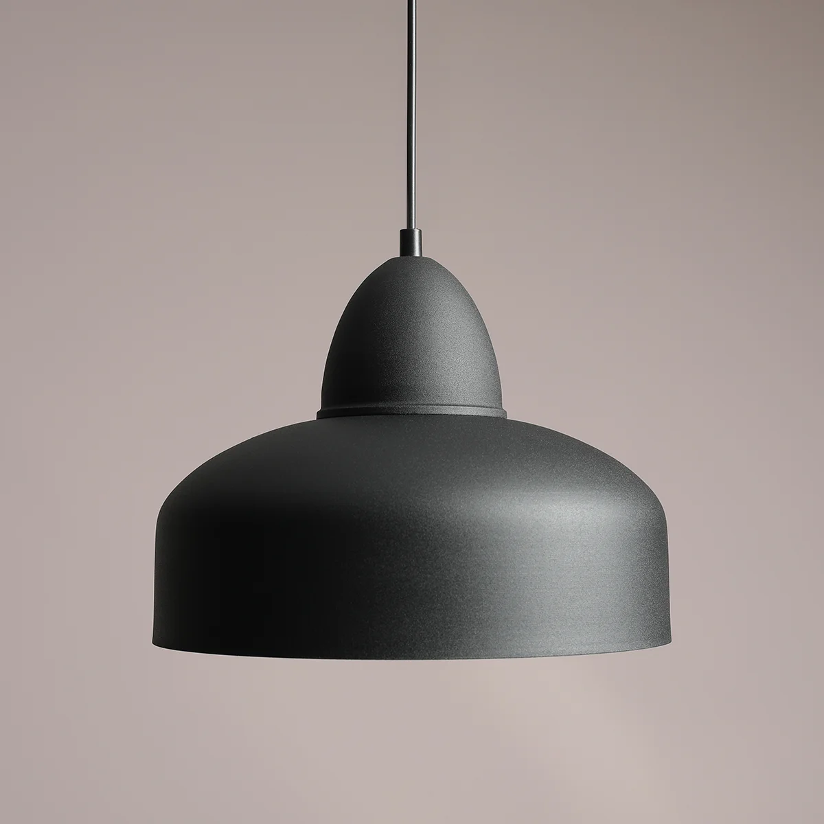 Lampa wisząca Como Black, 1-punktowa, o okrągłym kloszu w matowej czerni. Ujęcie z boku, ukazujące gładką powierzchnię i opływowy kształt. Zawieszona na cienkim przewodzie, na neutralnym tle.