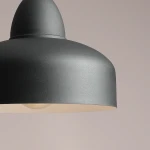 Czarna lampa wisząca Como 1-punktowa z matowym wykończeniem, o okrągłym kształcie. Widoczna oprawa z miejscem na żarówkę, zbliżenie na detal. Tło w jasnym odcieniu, podkreślające elegancki design.