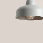 Lampa wisząca Como Gray w kolorze szarym, z metalowym kloszem o zaokrąglonym kształcie, z widoczną żarówką w środku. Kąt ujęcia z góry, na jednolitym tle.