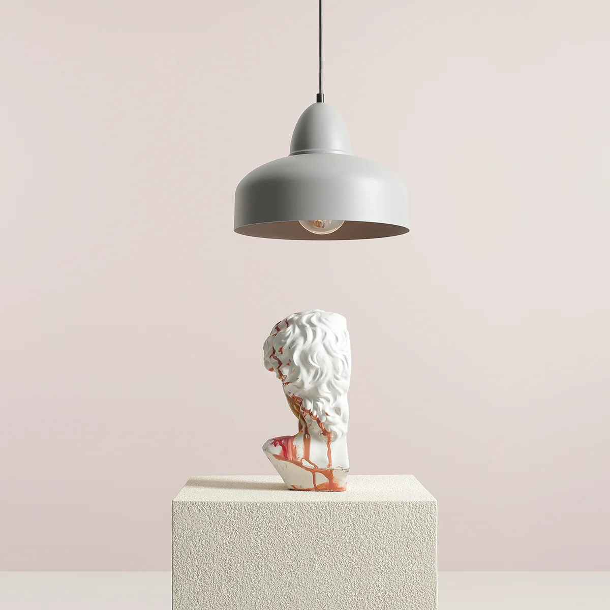 Lampa wisząca Como Gray w kolorze szarym z metalowym kloszem, zawieszona na cienkim kablu. Pod nią stoi biała figura z detalami w odcieniu brązu, na teksturowanym, jasnym podłożu. Tło w neutralnym odcieniu różu.