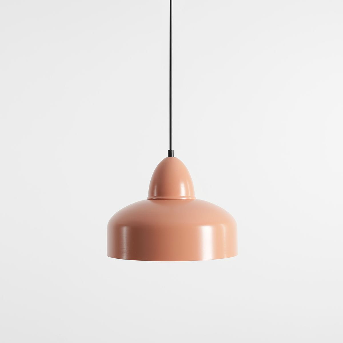 Lampa wisząca Como Coral 1-punktowa, w kolorze jasnoróżowym, o gładkiej, zaokrąglonej formie. Zawieszona na czarnym kabelku, z lekko wypukłym kloszem, prezentuje nowoczesny styl. Tło białe, minimalistyczne.
