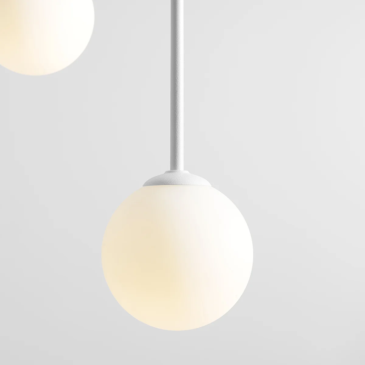 Lampa wisząca Bosso Ring 3-punktowa w kolorze białym. Posiada trzy okrągłe kula z mlecznego szkła zawieszone na cienkich białych linkach. Prosta konstrukcja, nowoczesny design, idealna do oświetlenia wnętrz.