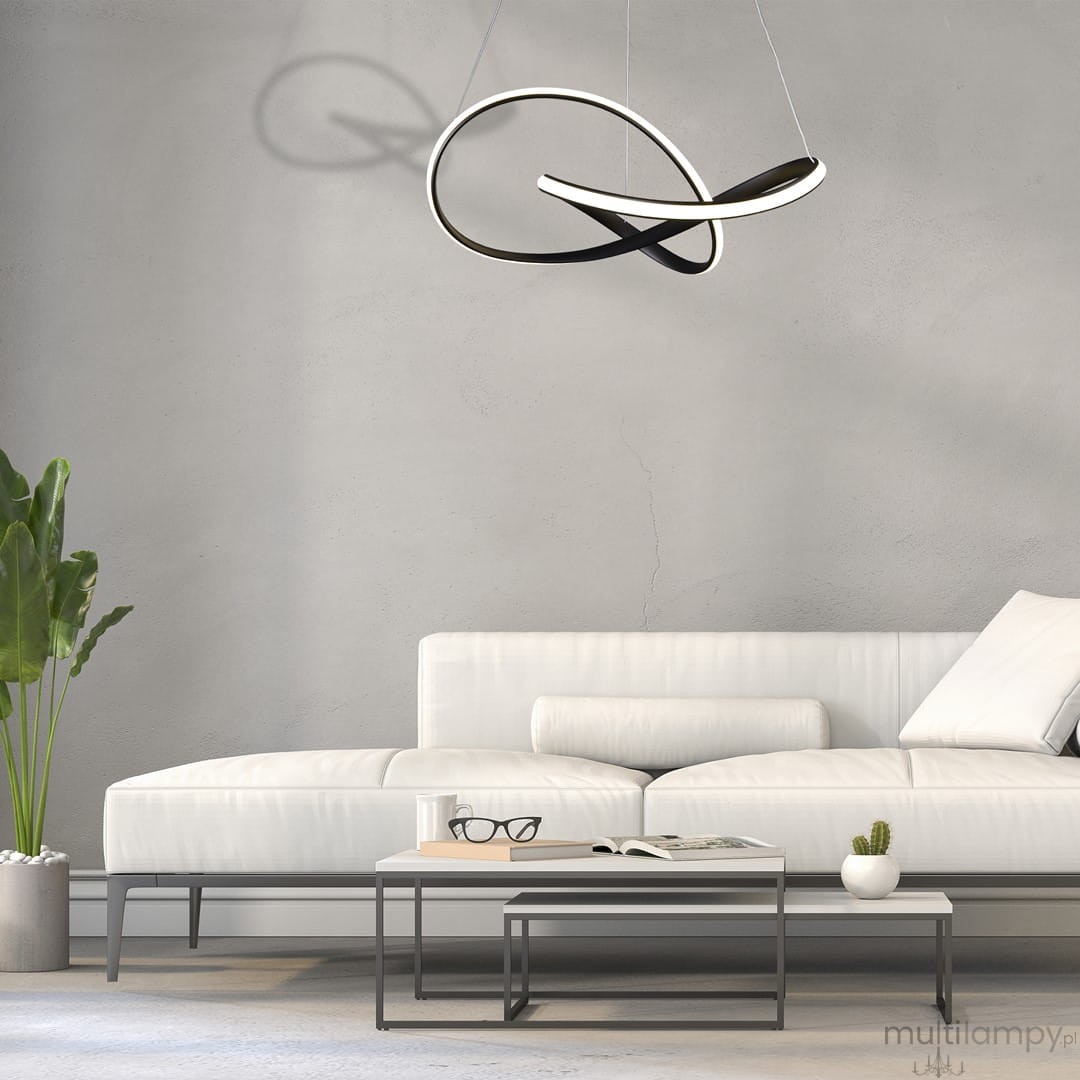 Cappio LED lampa wisząca 1-punktowa w czarnym kolorze, o nowoczesnym, abstrakcyjnym kształcie, zawieszona nad białą sofą w minimalistycznym wnętrzu. Tło w odcieniach szarości, z rośliną w doniczce oraz stolikiem kawowym z książkami i okularami.