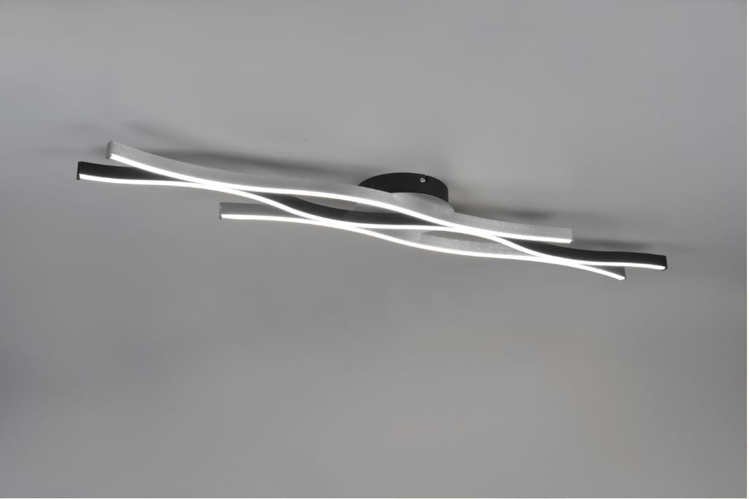 Srebrna lampa sufitowa LED Blaze z trzema punktami świetlnymi, o nowoczesnym, falistym kształcie. Lampa zamontowana na okrągłej podstawie, emituje delikatne światło z wąskich, teksturowanych pasów. Tło w kolorze szarym.