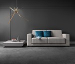 Lampa wisząca Spider LED 3-punktowa w kolorze złotym, z unikalnym kształtem składającym się z długich, asymetrycznych ramion. Zamontowana na cienkim przewodzie, znajduje się nad szarym sofą z niebieskimi poduszkami, w nowoczesnym wnętrzu.
