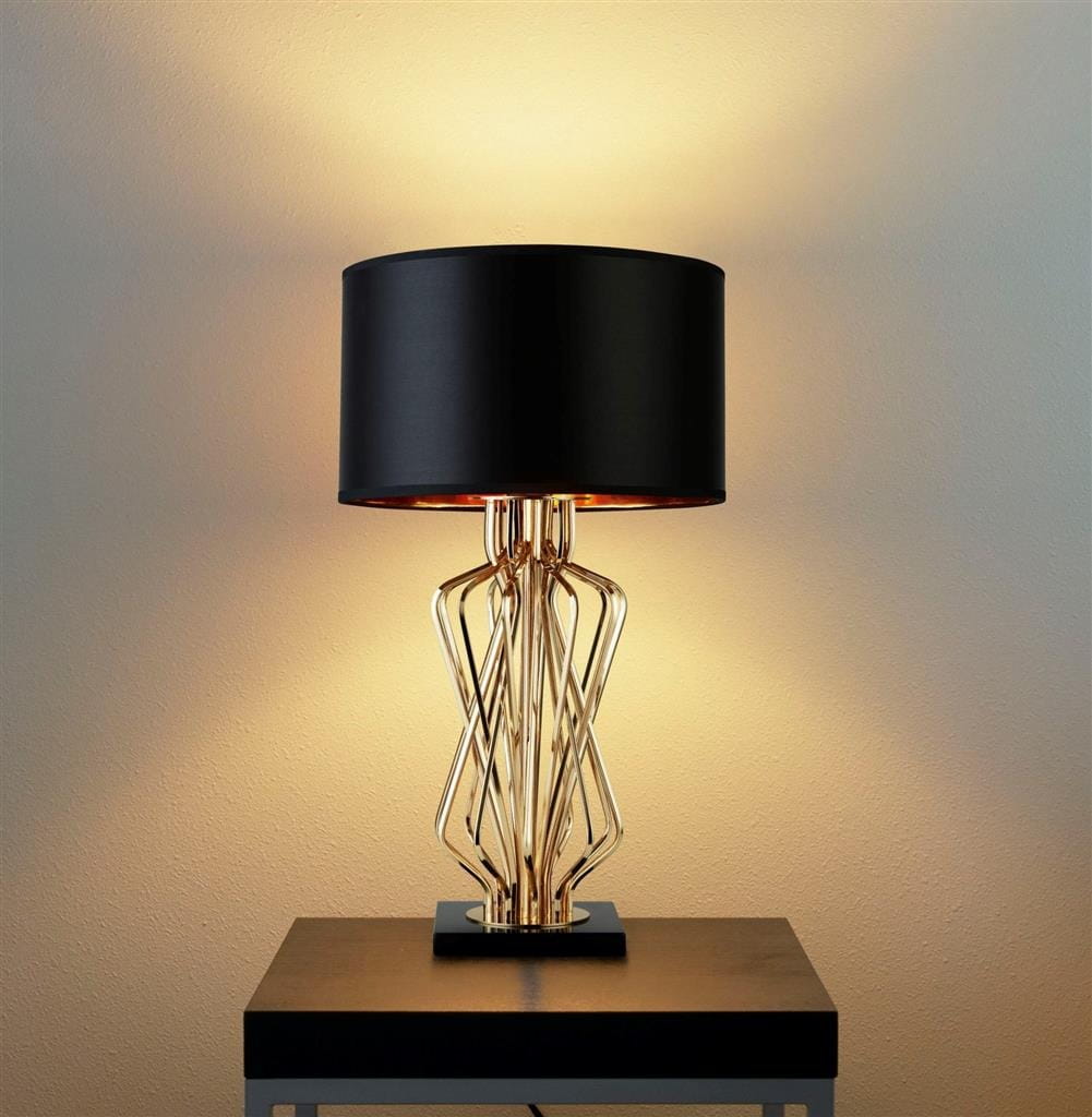 Lampa stołowa Ethan 1-punktowa w kolorze złotym z czarnym abażurem. Kształt podstawy przypomina faliste linie, umieszczona na prostokątnej podstawie. Lampa emituje ciepłe światło, tworząc przytulną atmosferę.