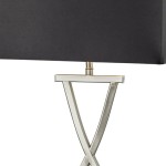 Lampa stołowa 1-punktowa w kolorze satynowego srebra z czarnym abażurem. Podstawa w kształcie litery X, wykonana z metalu. Abażur prostokątny, lekko zaokrąglony na krawędziach, umieszczony na metalowym ramieniu.