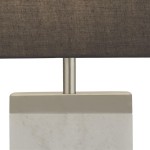 Lampa stołowa Naomi 1-punktowa, z podstawą z białego marmuru i satynowym niklowym stelażem. Ciemnoszary abażur z tkaniny, prosty kształt, stojąca, zbliżenie na detal u góry.