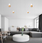 Lampa sufitowa Klemens tuba stała 1xGU10 w kolorze białym z złotym detalem, zamontowana na suficie. Widoczna w nowoczesnym wnętrzu z szarym narożnikiem i okrągłym stołem. Tło jasne, minimalistyczne, z elementami drewnianymi.