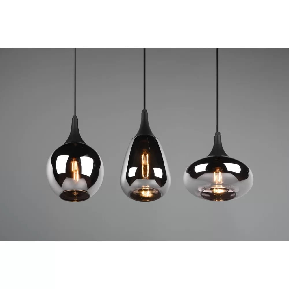 Lampa wisząca Lumina 3-punktowa w kolorze czarnym i chromowanym. Posiada trzy różne klosze: w kształcie kropli, owalnym i okrągłym, wykonane z transparentnego materiału. Zawieszona na cienkich linkach, prezentuje się na szarym tle.