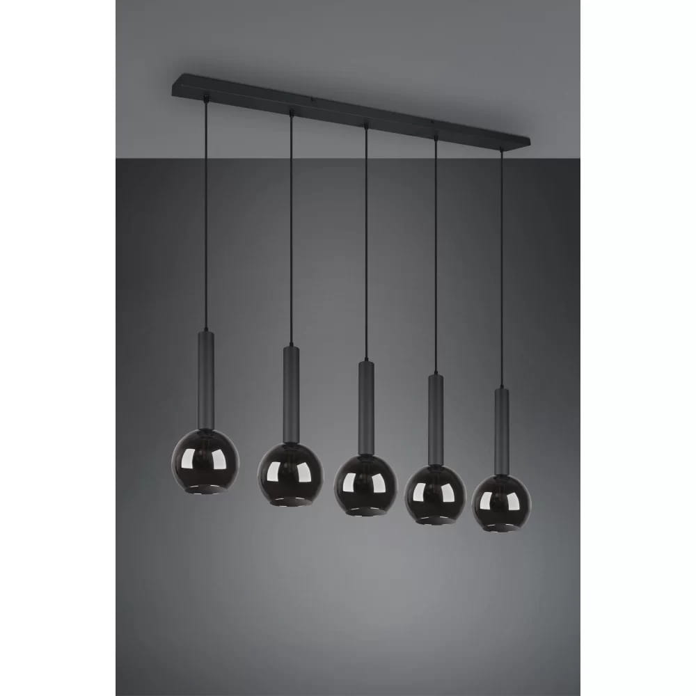 Czarna lampa wisząca Clayton z pięcioma punktami świetlnymi, składająca się z okrągłych kloszy, zawieszona na długich, smukłych linkach, zamontowana na prostokątnej podstawie. Idealna do nowoczesnych wnętrz.