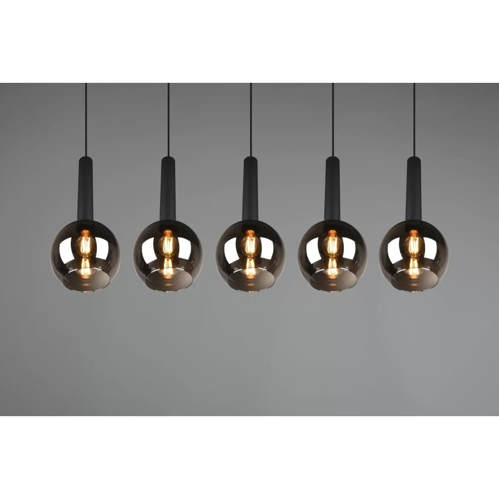 Lampa wisząca Clayton 5-punktowa, czarna, z pięcioma szklanymi kloszami w kształcie kul, zawieszona na cienkich linkach. Klosze mają ciemne, lekko przejrzyste wykończenie, a wewnątrz widoczne żarówki. Tło w odcieniu szarym.