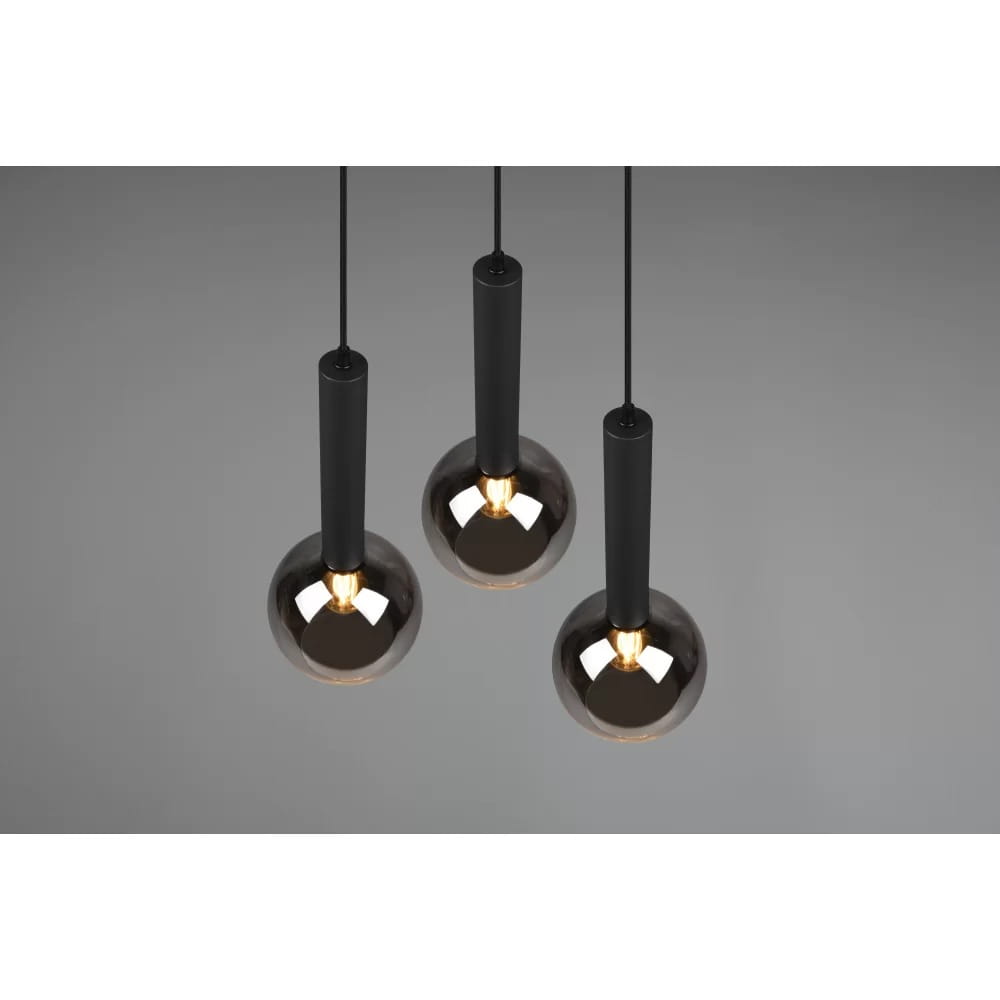 Czarna lampa wisząca Clayton z trzema punktami świetlnymi, złożona z cylindrycznych, matowych uchwytów oraz kulistych, szklanych kloszy w ciemnym kolorze. Produkt zawieszony na cienkich linkach, z widocznym źródłem światła w każdej lampie.