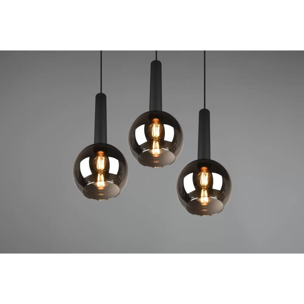 Lampa wisząca Clayton 3-punktowa w kolorze czarnym, z trzema okrągłymi kloszami w ciemnym, przezroczystym szkle. Klasyczne, minimalistyczne wykończenie, zawieszona na cienkich linkach, prezentująca nowoczesny styl.