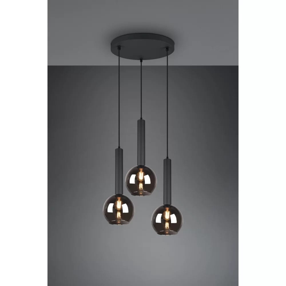 Czarna lampa wisząca Clayton z trzema punktami świetlnymi. Każda kula ma szklany klosz w odcieniu dymnym, zawieszona na cienkich czarnych linkach. Uchwyt sufitowy w kolorze czarnym, całość na jednolitym, szarym tle.