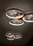 Czarna, trójpunktowa lampa sufitowa Groovy 3000K z okrągłymi kloszami. Oświetlenie z delikatnymi, przezroczystymi detalami w kształcie kropli, umieszczonymi na złotych gałązkach. Lampa zamontowana na sufit, w eleganckim, nowoczesnym stylu.