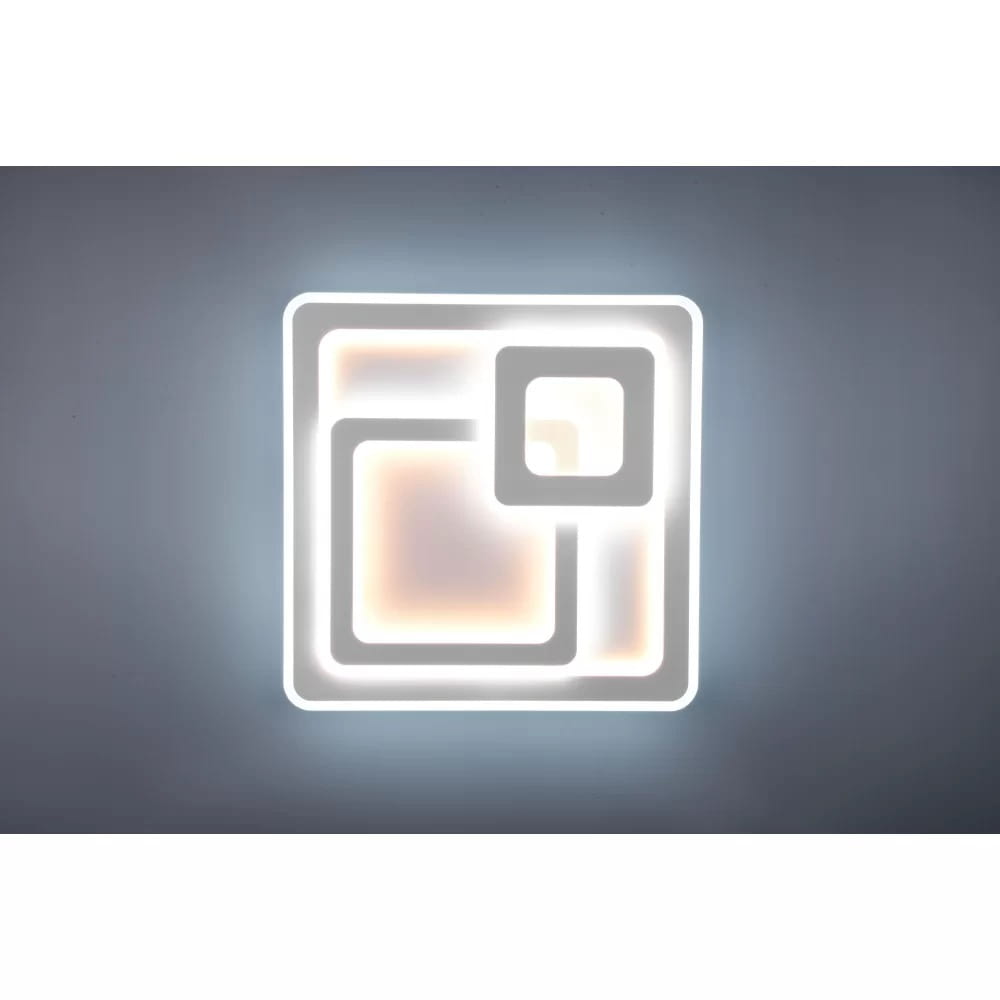 Biała lampa sufitowa Mita LED 3-punktowa z pilotem, o nowoczesnym, kwadratowym kształcie. Widoczne dwa zagnieżdżone prostokąty z podświetleniem, na jednolitym tle. Lampa zamontowana na suficie, w pozycji zamkniętej.