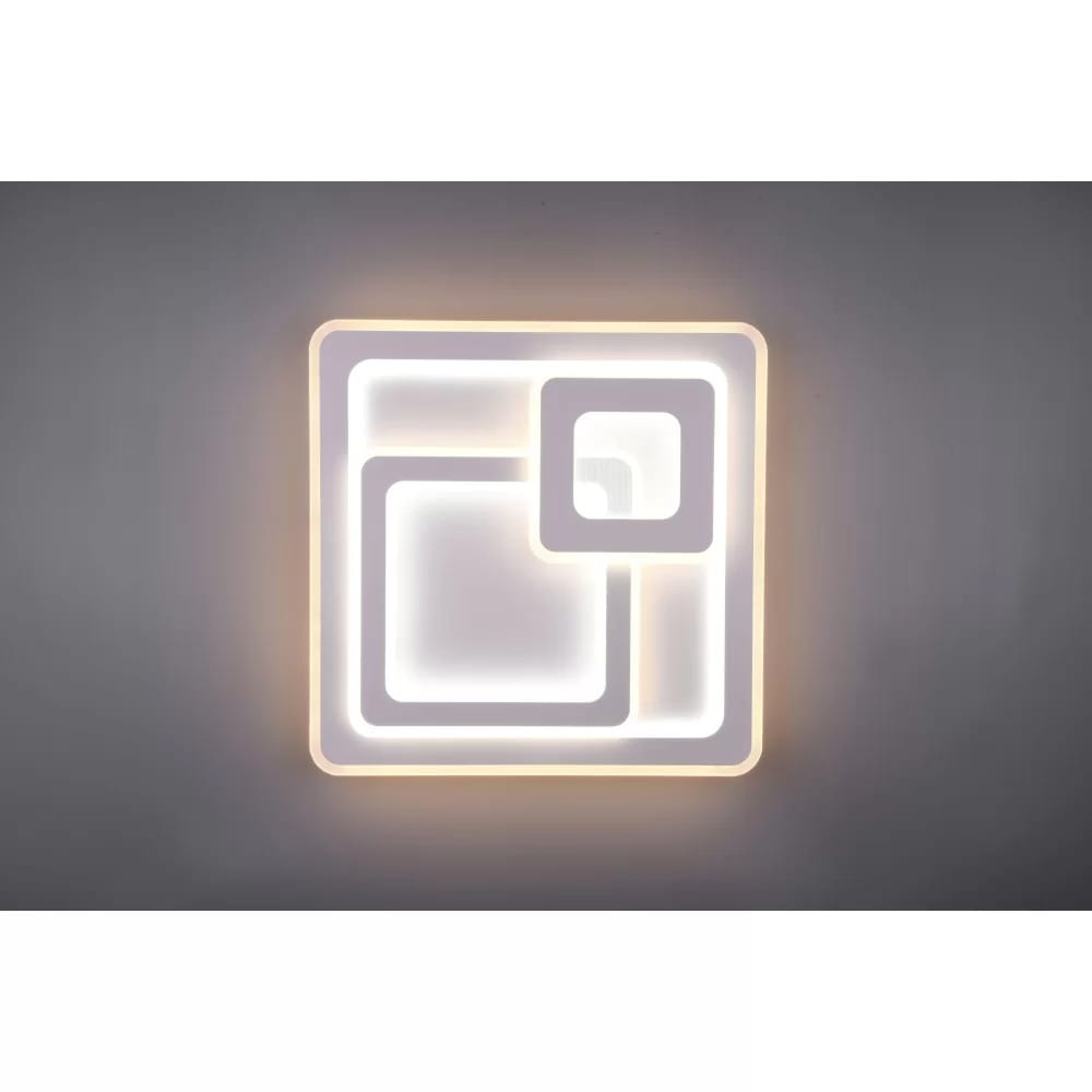 Mita LED lampa sufitowa 3-punktowa w kolorze białym z pilotem, o nowoczesnym kształcie składającym się z dwóch nachodzących na siebie kwadratów. Lampa emituje ciepłe światło, zamontowana na szarym tle.