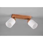 Lampa sufitowa Assam, 2-punktowa, z drewnianą podstawą w kolorze naturalnym. Posiada dwa białe klosze w kształcie cylindra, umieszczone na metalowych uchwytach. Produkt zamontowany na szarym tle.