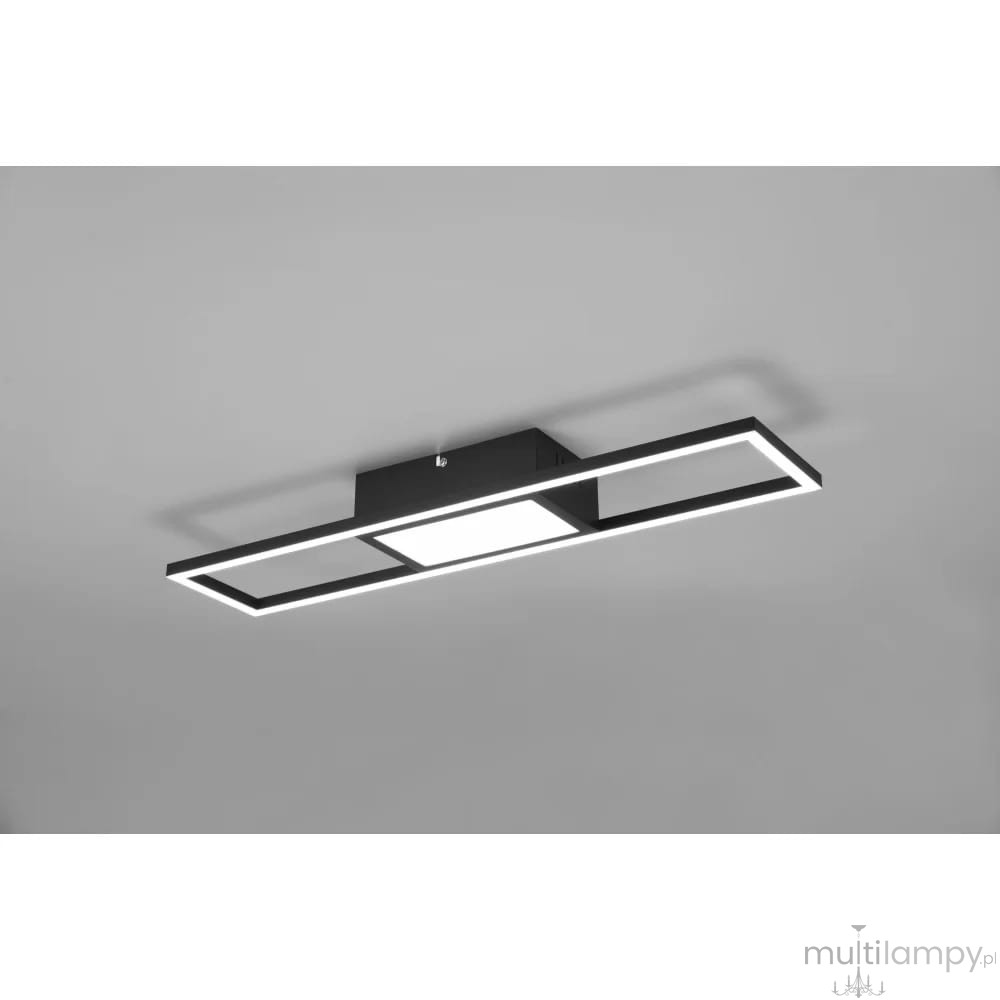 Czarna lampa sufitowa Rigido LED w prostokątnym kształcie, z centralnym panelem świetlnym otoczonym cienkimi ramkami. Lampa zamontowana na suficie, z możliwością sterowania pilotem. Prosty, nowoczesny design na jasnym tle.