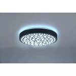 Czarny plafon LED Chizu z pilotem, okrągły, z dekoracyjnym wzorem w postaci perforacji. Emituje kolorowe światło RGB, widoczny delikatny niebieski blask wokół krawędzi. Zawieszony na suficie, w prostym otoczeniu.