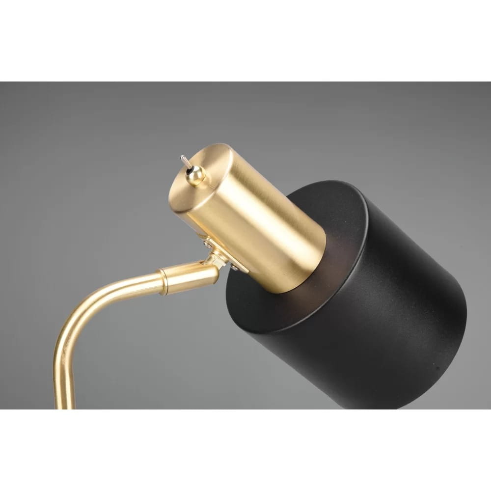 Lampa stołowa Adam 1-punktowa w kolorze złotym i czarnym. Widok z góry na metalową, cylindryczną podstawę w czerni oraz złoty klosz z przyciskiem. Stylowy, minimalistyczny design z zaokrąglonym ramieniem. Tło szare.