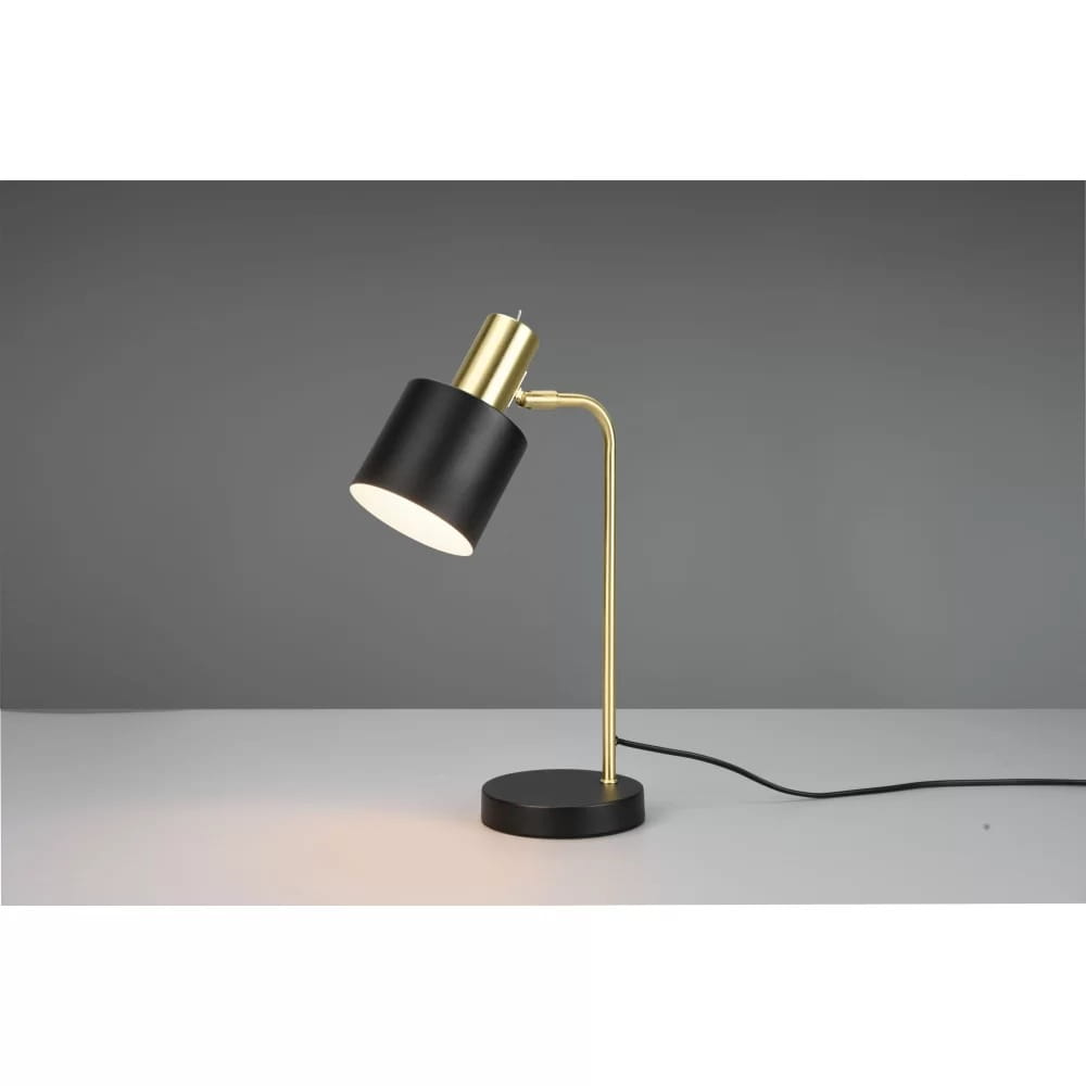 Lampa stołowa Adam 1-punktowa w kolorze złotym i czarnym. Podstawa okrągła czarna, smukły, złoty stelaż z regulowanym kloszem w czerni. Kąt ujęcia z boku, na jednolitym tle, z widocznym przewodem.