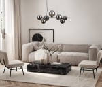 Lampa wisząca Canello 7-punktowa w kolorze czarnym chromowanym z dymionymi kloszami, zawieszona nad stolikiem kawowym w nowoczesnym wnętrzu. W tle widoczne jasne zasłony i grafika na ścianie. Meble w odcieniach beżu i czerni.