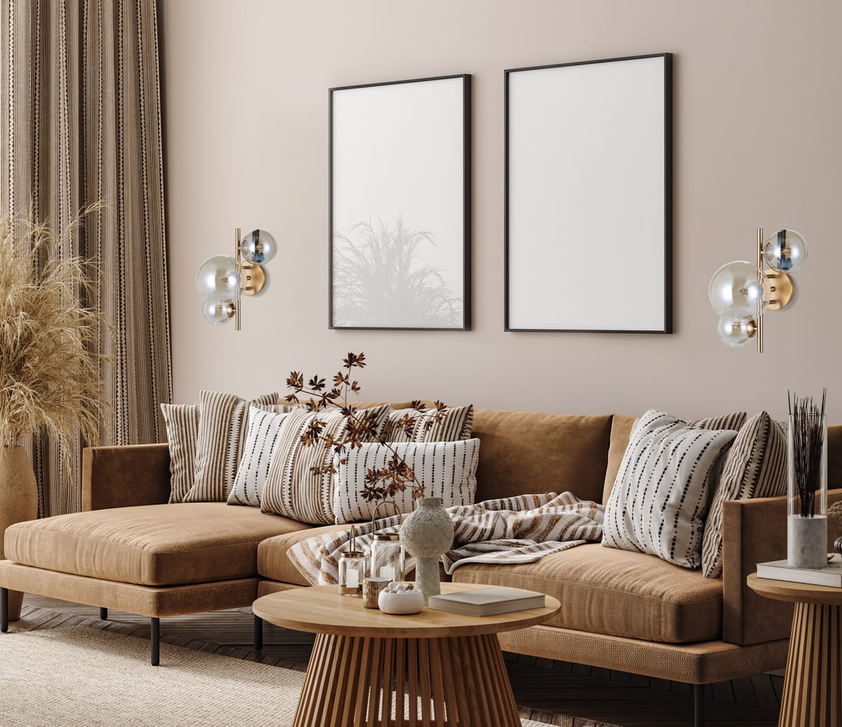 Kinkiet Canello 3-punktowy w kolorze mosiądzu i bursztynu, z trzema szklanymi kloszami, zamontowany na ścianie obok kanapy. W tle widoczne są zasłony i puste ramki na zdjęcia. Jasny, elegancki styl wnętrza.