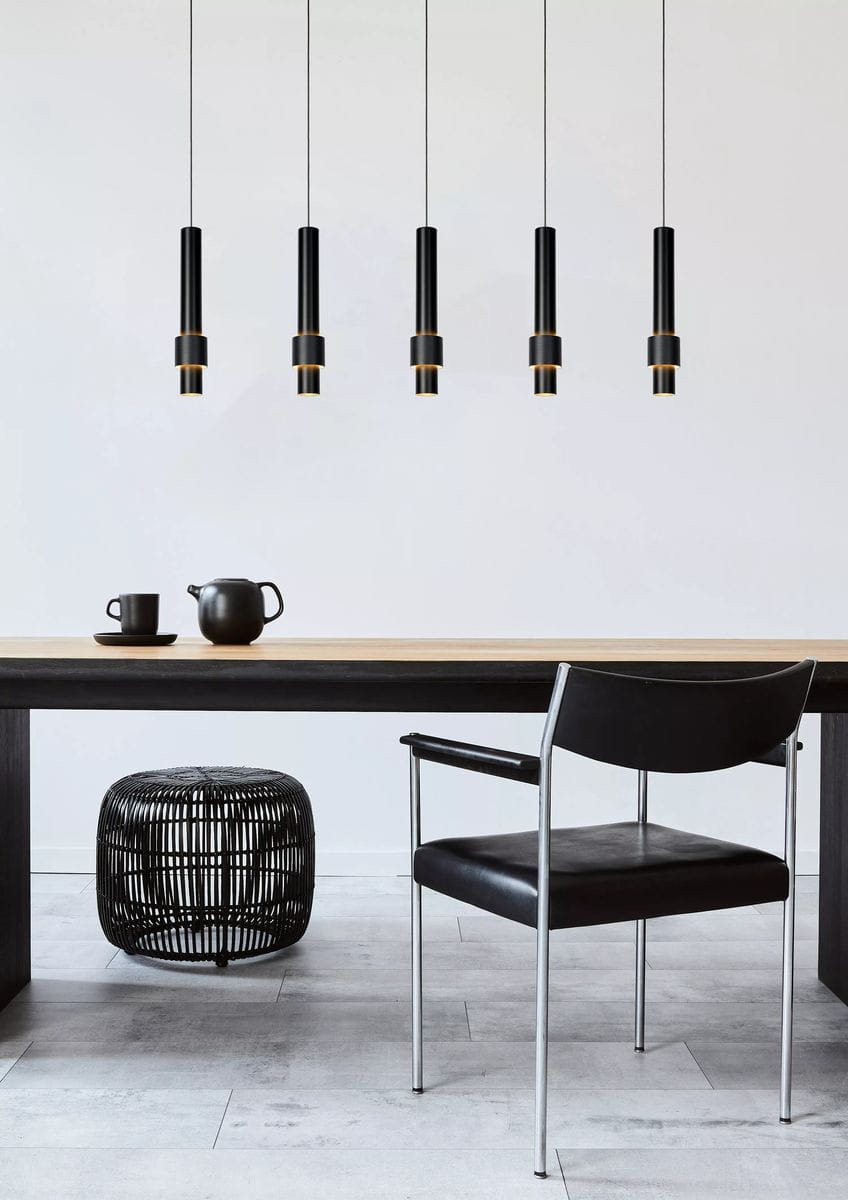 Margary LED lampa wisząca 5-punktowa w kolorze czarnym z elementami metalowymi, zawieszona na cienkich linkach. Lampa składa się z pięciu cylindrycznych kloszy, umieszczonych nad drewnianym stołem, w nowoczesnym wnętrzu.